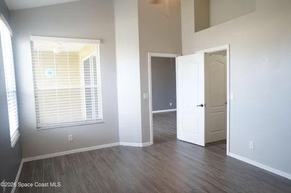 an empty room with wooden floor & windows