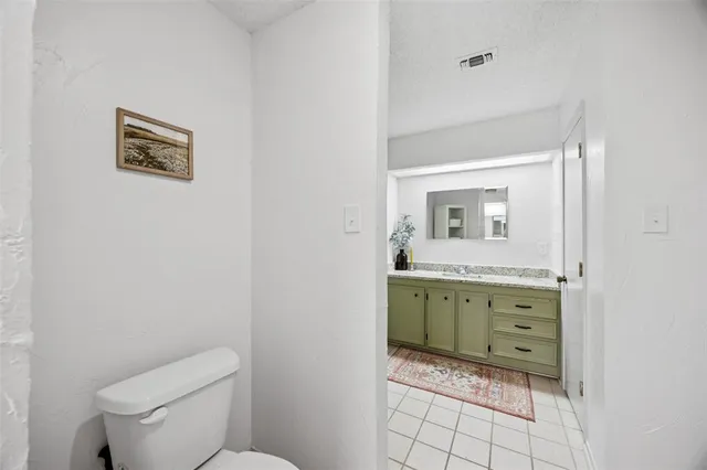 a bathroom with a granite countertop toilet sink and mirror