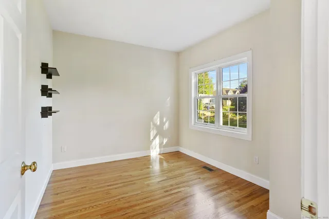 a view of an empty room with window and wooden floor