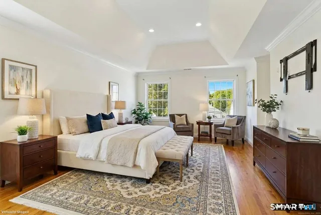 a bedroom with a bed a potted plant on dresser and a wooden floor