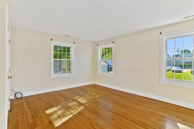 a view of an empty room with window and wooden floor