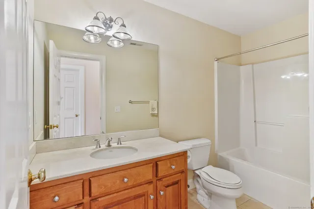 a bathroom with a granite countertop sink a toilet a mirror and shower