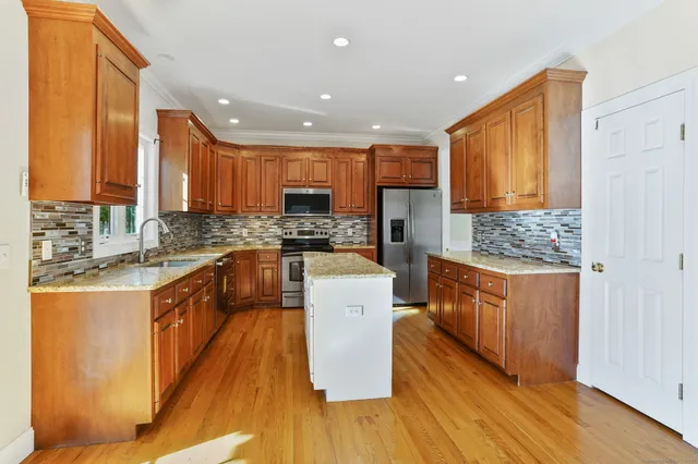 a large kitchen with stainless steel appliances granite countertop a stove a sink dishwasher and a refrigerator with wooden floor
