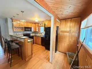 a kitchen with stainless steel appliances kitchen island granite countertop a refrigerator a stove a sink a dining table and chairs with wooden floor