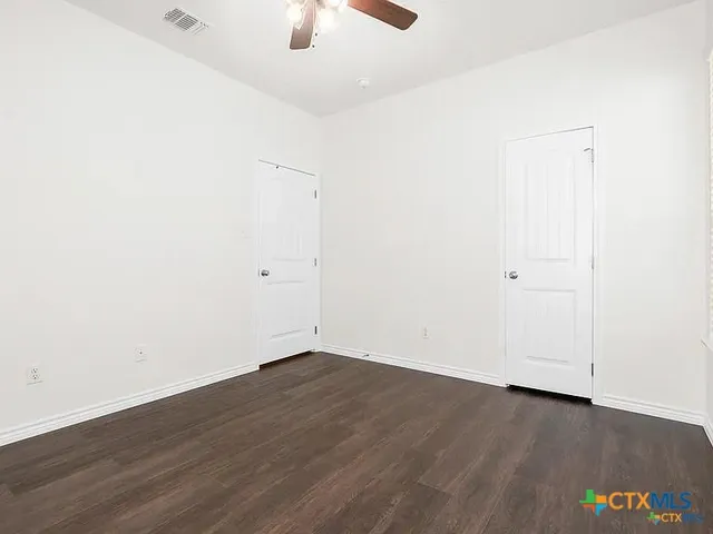 an empty room with wooden floor and fan