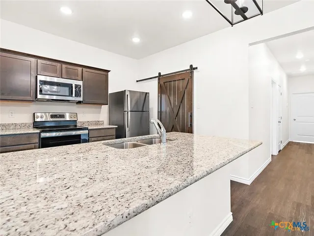 a kitchen with stainless steel appliances granite countertop a refrigerator and a sink