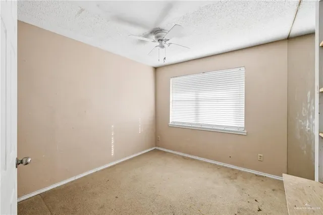 an empty room with a window and a ceiling fan