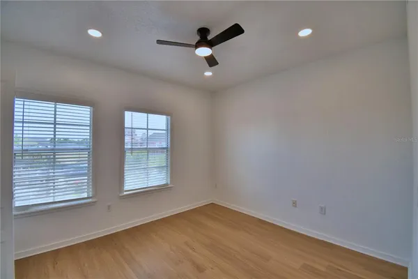 a view of an empty room with a window and wooden floor