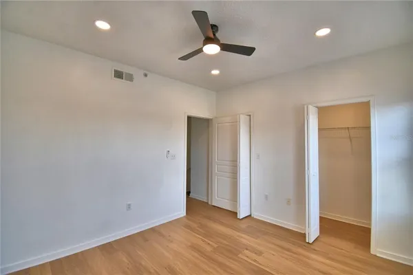 an empty room with wooden floor ceiling fan and window