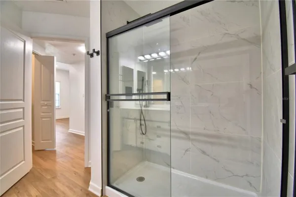 an empty room with wooden floor ceiling fan and windows