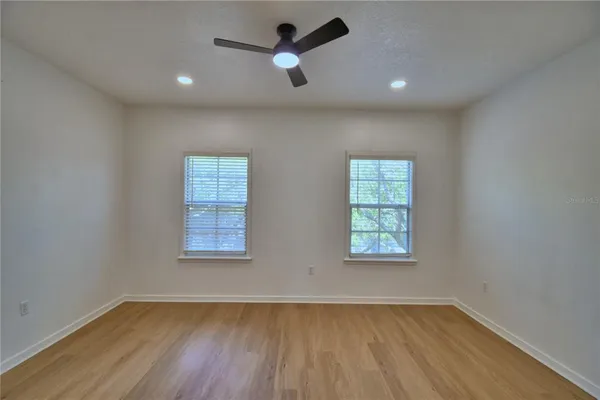 an empty room with wooden floor and windows