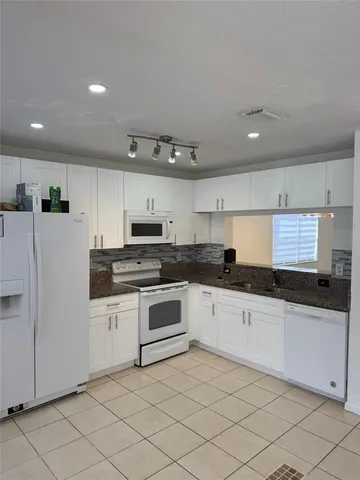 a kitchen with granite countertop white cabinets and white appliances