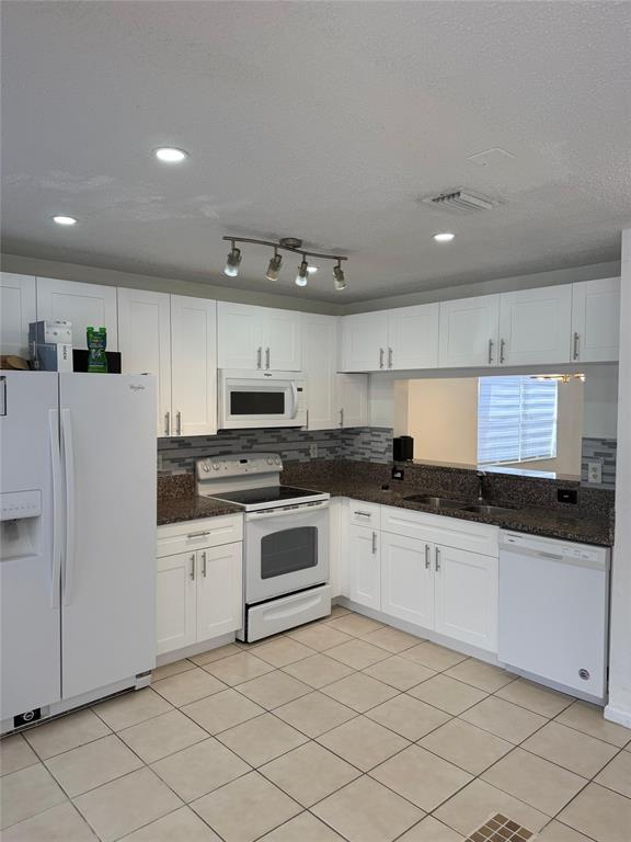4243 Northwest 68 Way, Unit 4243 Fort Lauderdale, FL 33319 - Photo 12 of 15 a kitchen with granite countertop white cabinets and white appliances