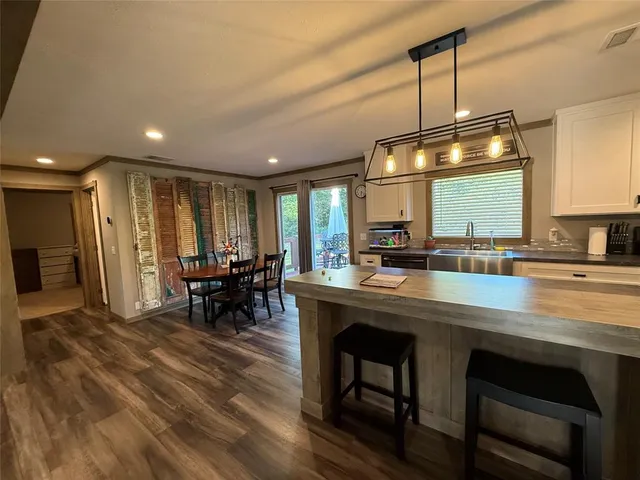 a kitchen with stainless steel appliances granite countertop a table chairs sink and stove top oven