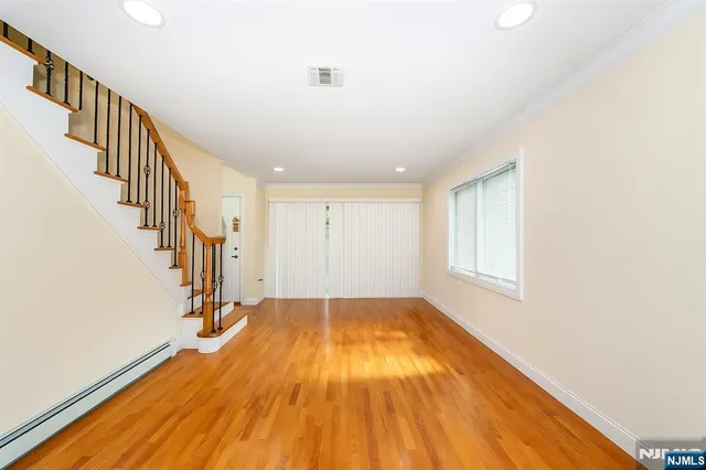 a view of an empty room with wooden floor and stairs