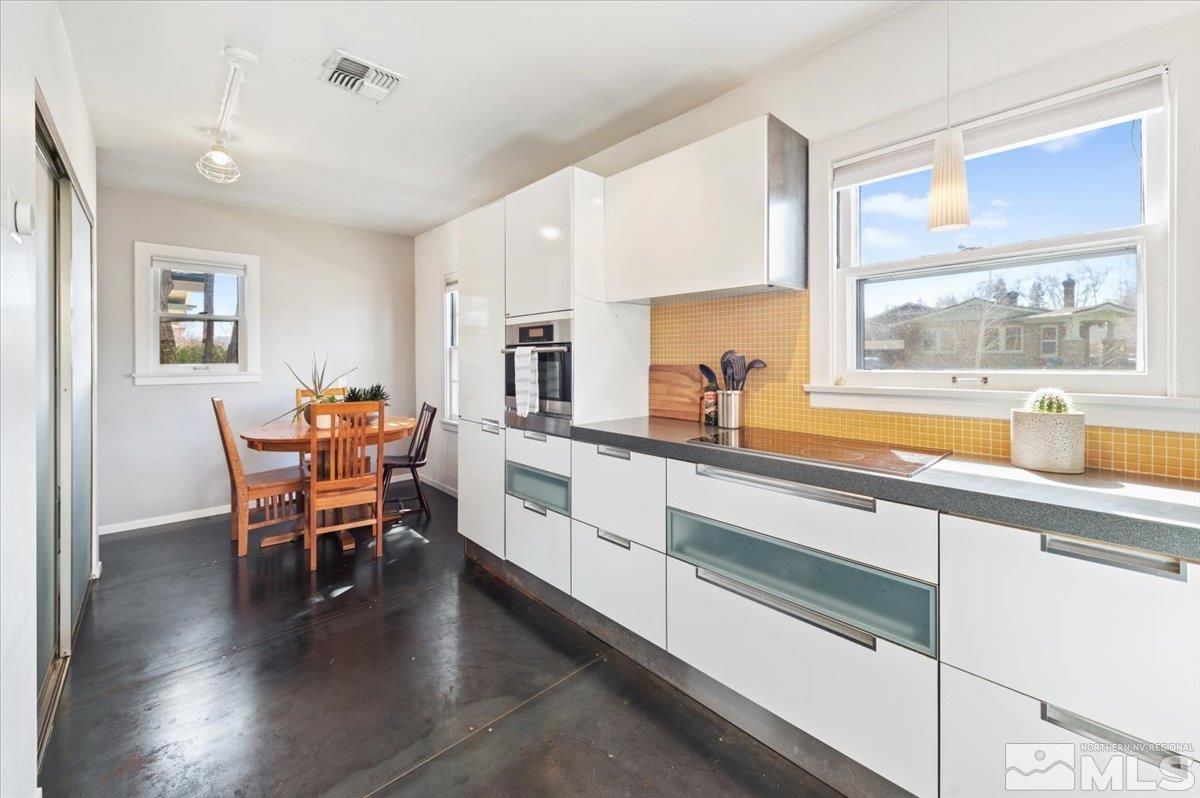 1250 Watt Street Reno, NV 89509 - Photo 13 of 33 a open kitchen with stainless steel appliances granite countertop a stove a sink a dining table and chairs with wooden floor