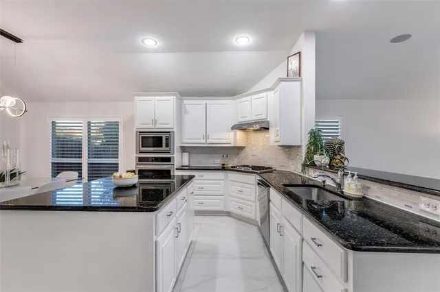 a kitchen with granite countertop a sink and a stove top oven