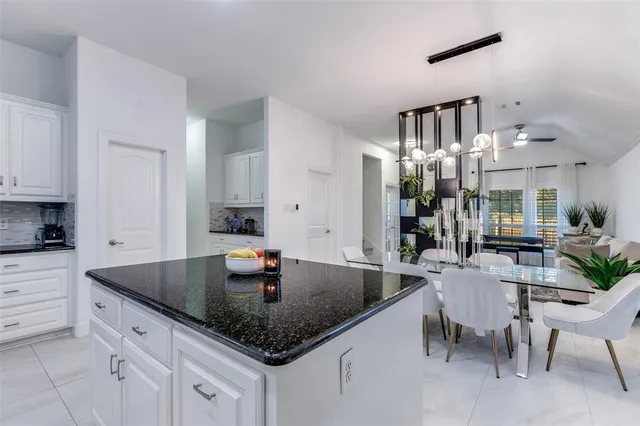 a kitchen with granite countertop a sink white cabinets and chairs