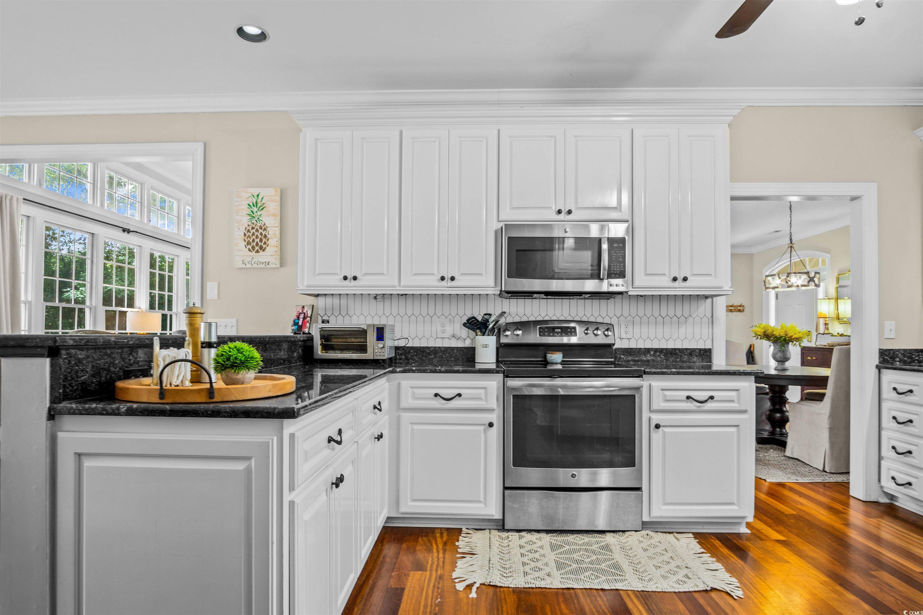 1079 Waterway Lane Myrtle Beach, SC 29572 - Photo 2 of 38 Kitchen with white cabinets, appliances with stainless steel finishes, dark stone counters, dark wood-style floors, and crown molding
