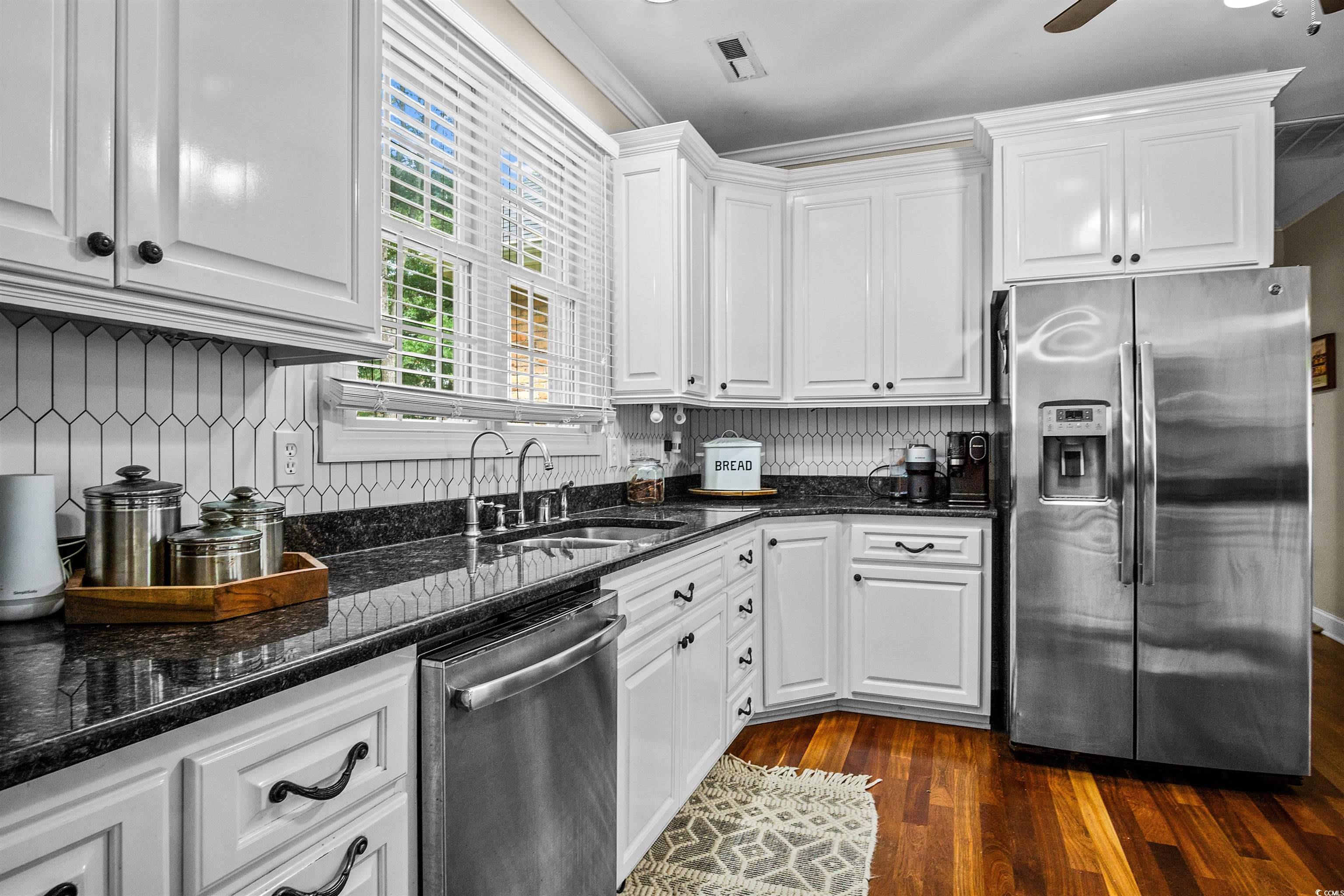 1079 Waterway Lane Myrtle Beach, SC 29572 - Photo 3 of 38 Kitchen featuring dark stone countertops, appliances with stainless steel finishes, dark wood-style floors, white cabinets, and ornamental molding