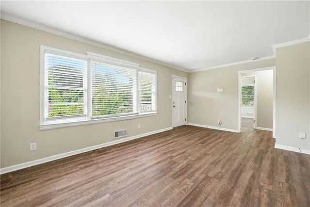 a view of an empty room with wooden floor and a window
