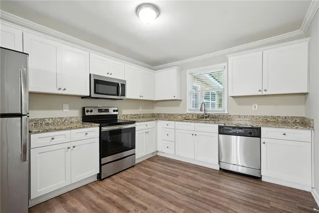 a kitchen with granite countertop white cabinets and appliances