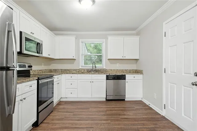 a kitchen with granite countertop white cabinets and white appliances