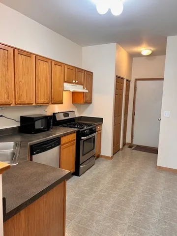 a kitchen with granite countertop a stove a sink and a refrigerator