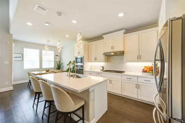 a kitchen with stainless steel appliances a table chairs and a refrigerator