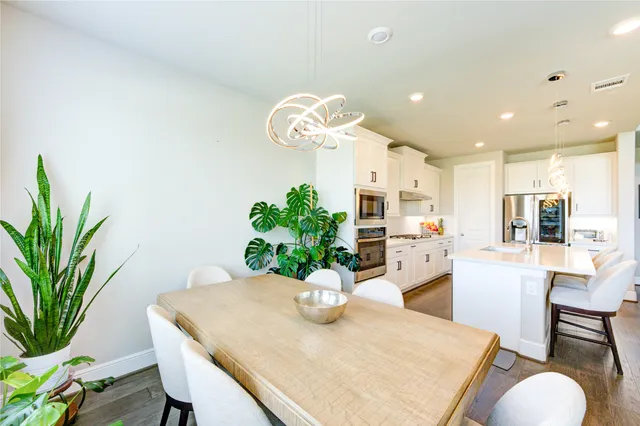 a dining room with furniture a potted plant and a kitchen view