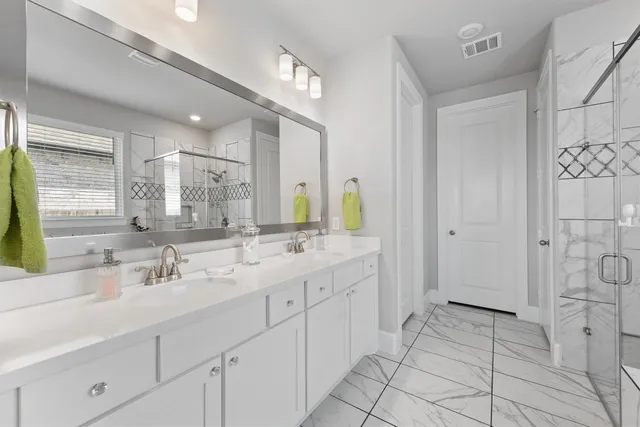 a bathroom with a double vanity sink mirror and shower