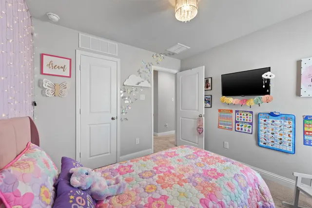 a bedroom with a bed and a flat tv screen on dresser