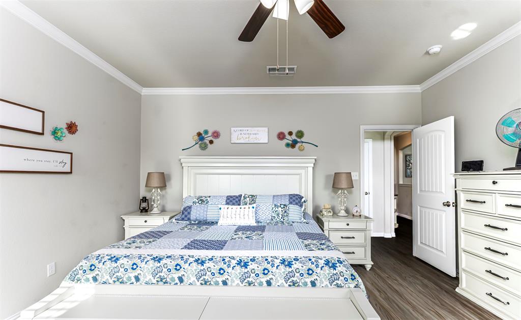 129 Springwood Ranch Loop Springtown, TX 76082 - Photo 16 of 29 Bright primary bedroom showcasing a white shaker-style headboard with integrated storage, wood-finish flooring, ceiling fan with integrated lighting, recessed ceiling lights, and direct access to an ensuite bathroom and walk-in closet
