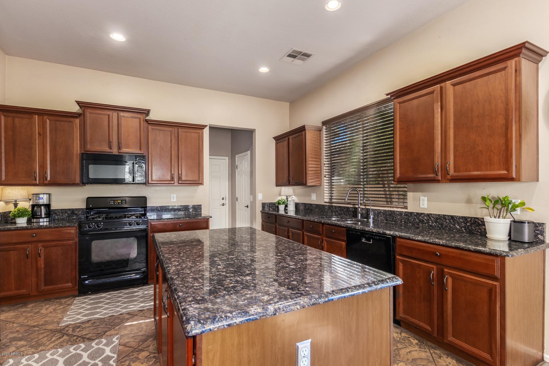 1043 Phelps Street Gilbert, AZ 85295 - Photo 2 of 18 a kitchen with stainless steel appliances granite countertop wooden cabinets a stove top oven a granite counter and a sink