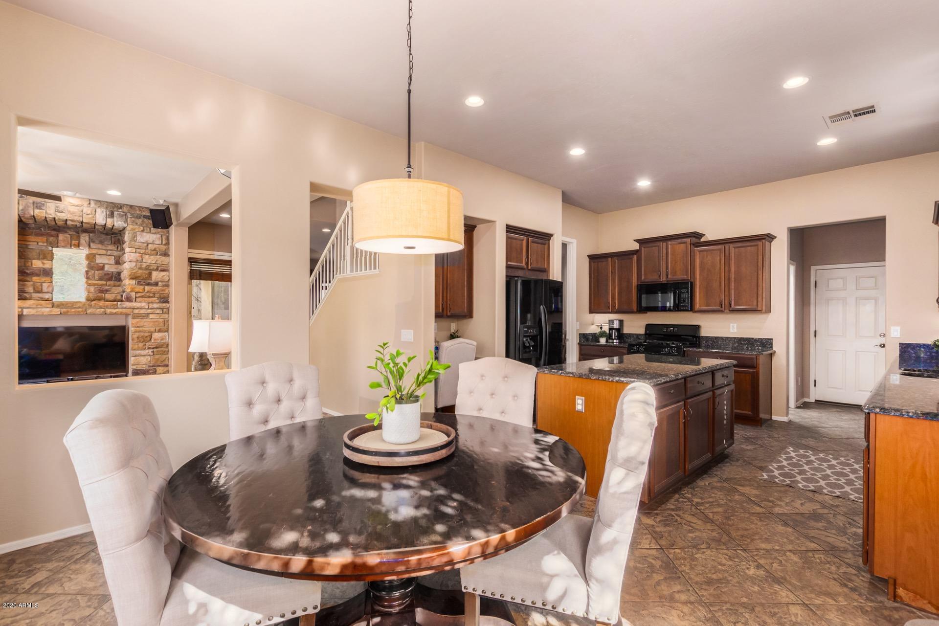 1043 Phelps Street Gilbert, AZ 85295 - Photo 4 of 18 a kitchen with stainless steel appliances kitchen island granite countertop a sink a stove a dining table and chairs