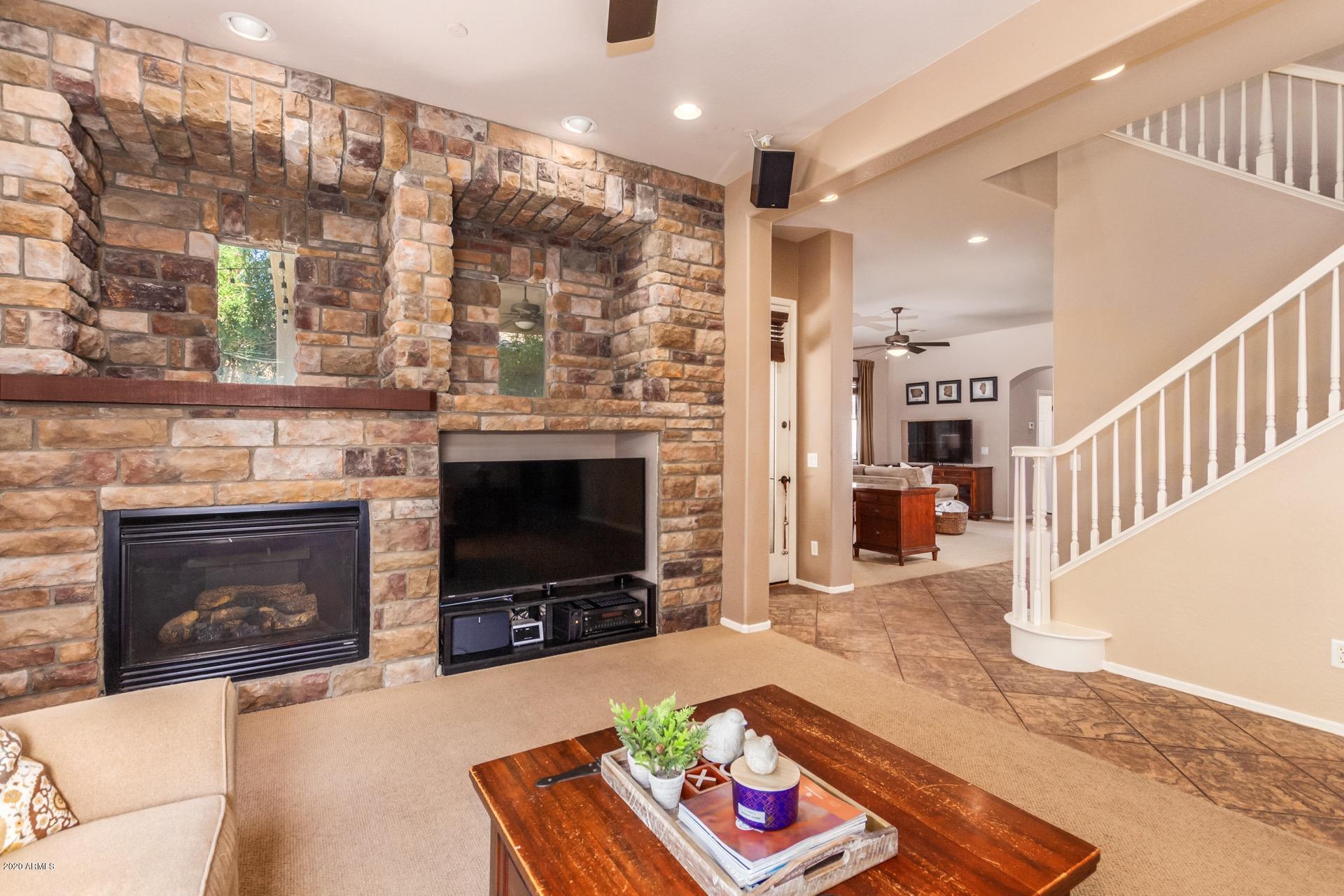 1043 Phelps Street Gilbert, AZ 85295 - Photo 5 of 18 a living room with furniture a flat screen tv and a fireplace