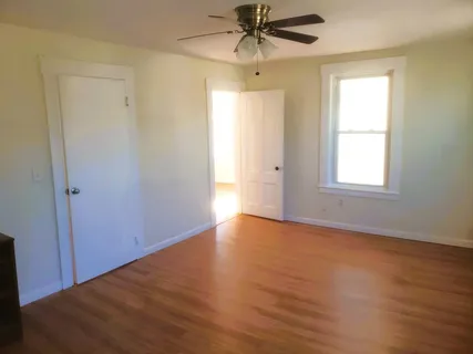 an empty room with wooden floor closet and windows