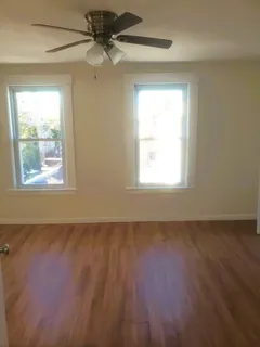 an empty room with wooden floor and windows