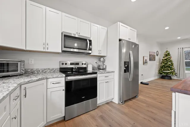 a kitchen with stainless steel appliances granite countertop a refrigerator stove and white cabinets