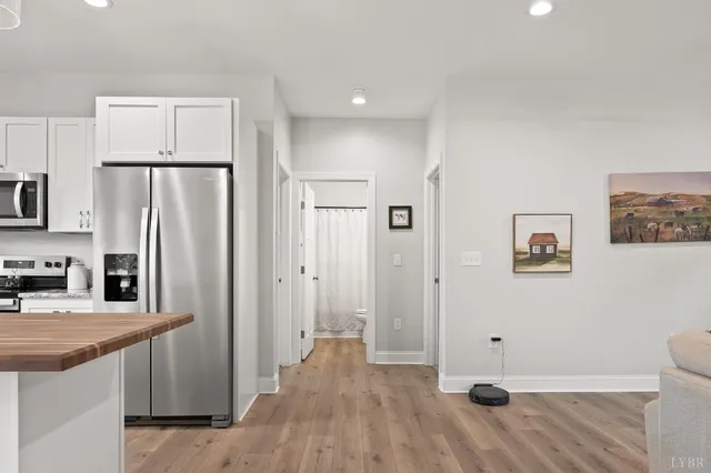 a view of kitchen with stainless steel appliances wooden floor and cabinets