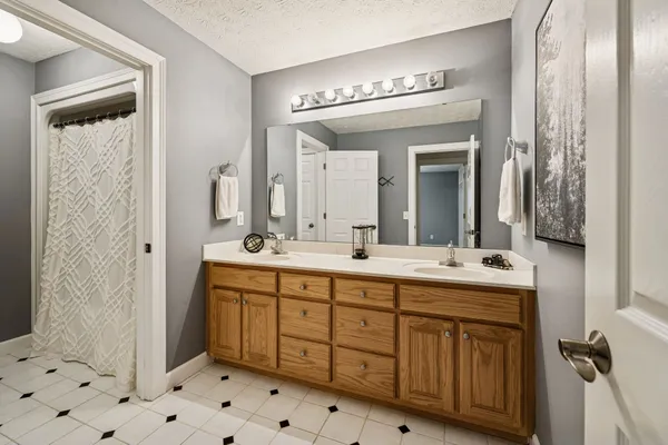 a spacious bathroom with a double vanity sink a mirror and a shower