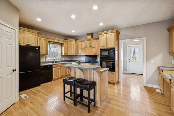 a kitchen with granite countertop a refrigerator stove microwave and cabinets with wooden floor