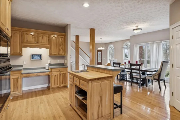 a kitchen with stainless steel appliances granite countertop a stove top oven a sink dishwasher a dining table and chairs with wooden floor