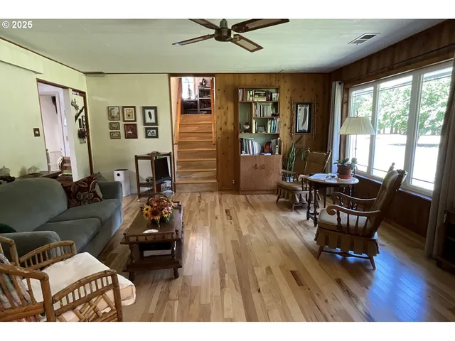 a living room with furniture two window and wooden floor