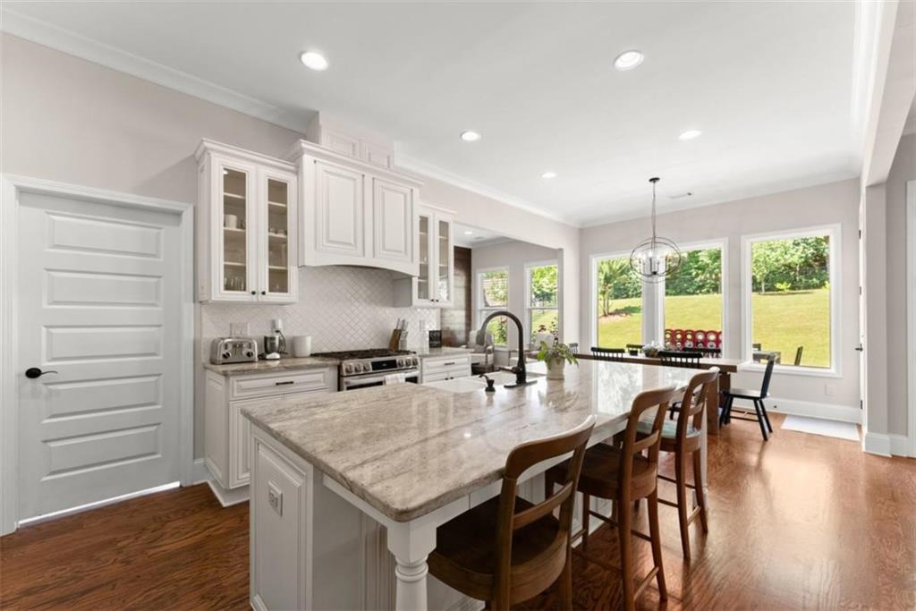 845 Walnut River Trail Hoschton, GA 30548 - Photo 31 of 74 a kitchen with granite countertop a stove a table and chairs in it