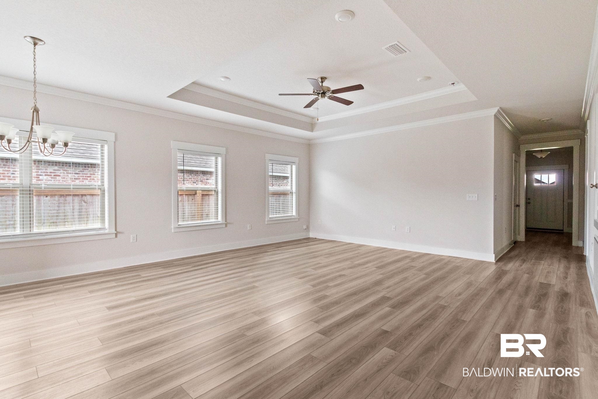 1710 Grouse Street Foley, AL 36535 - Photo 21 of 76 Spacious living area featuring wood-finish flooring, a tray ceiling with a ceiling fan, recessed lighting, and multiple windows with blinds