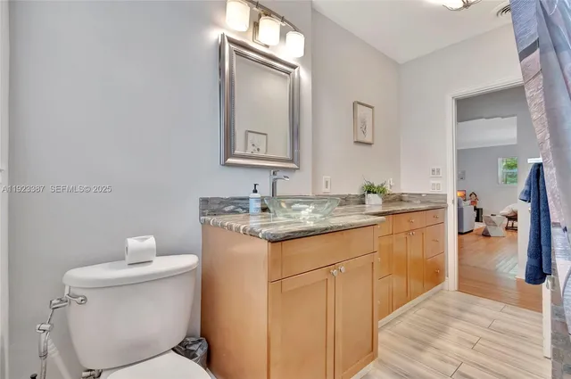 a bathroom with a granite countertop sink toilet and mirror