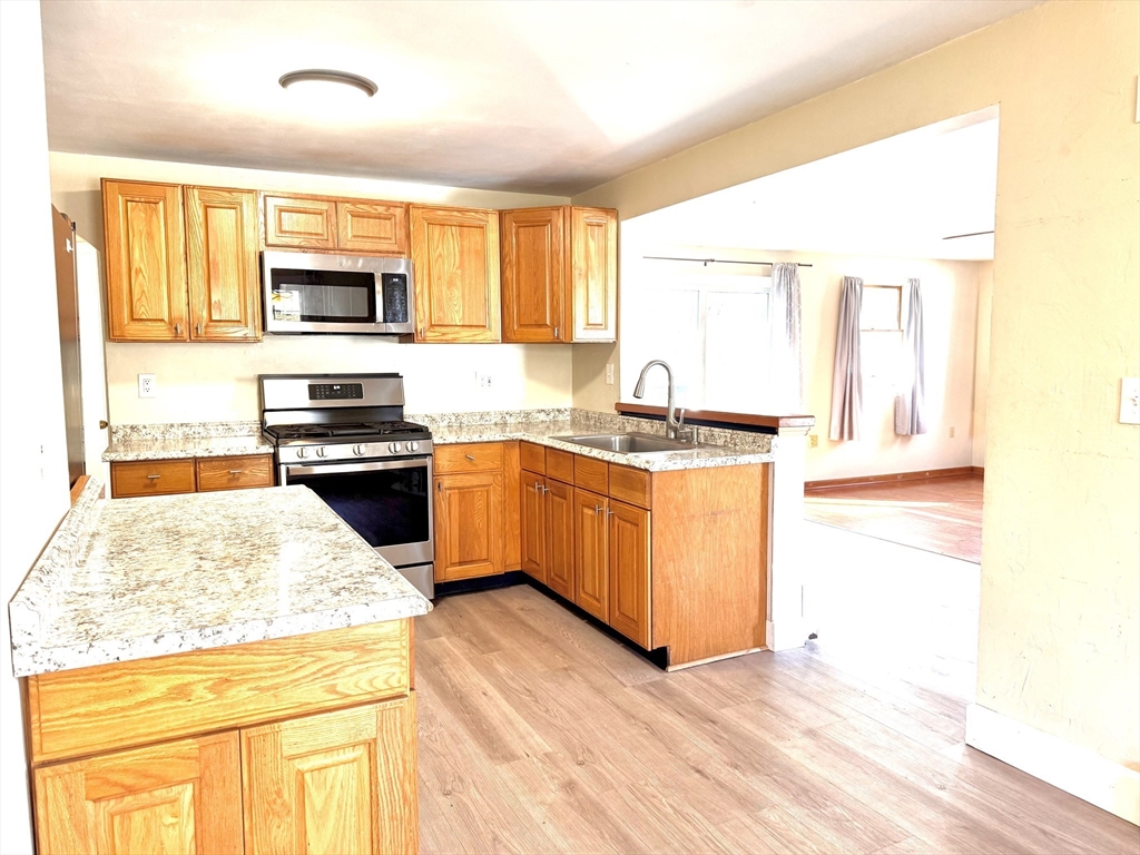 9 Redfield Road Cherry Valley, MA 01611 - Photo 19 of 35 a kitchen with stainless steel appliances granite countertop a stove a sink and white cabinets with wooden floors