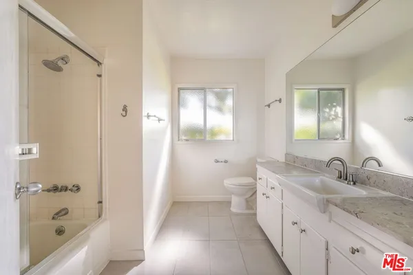a bathroom with a granite countertop sink a toilet and shower