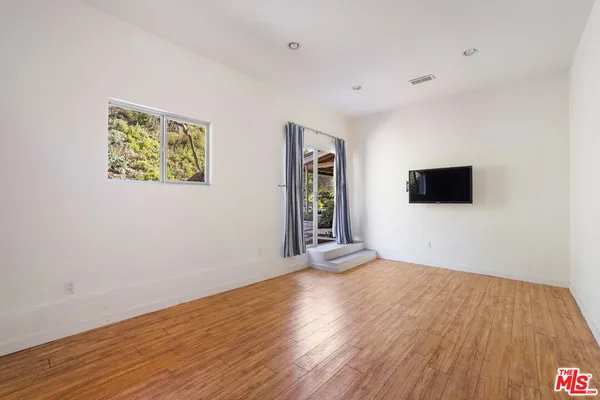 a view of an empty room with wooden floor and a window
